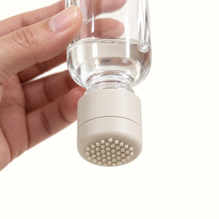 Product visualization of a hand holding a compatible serum bottle upside down with the APLD applicator attached.